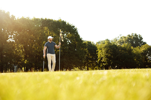 storyblocks-male-golfer-putting-flag-in-hole-at-green-golf-course_rCNkauh6cZ